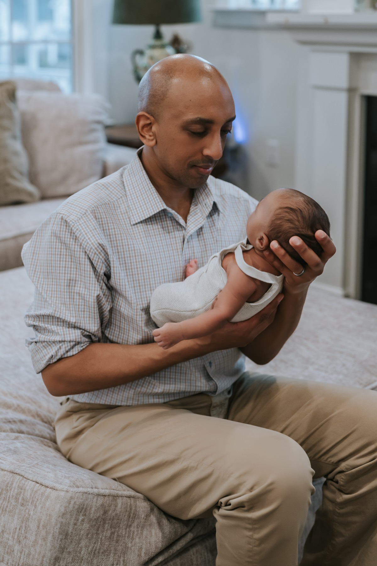Father sitting on the couch, cradling newborn Yohannes in his arms and gazing down at him lovingly