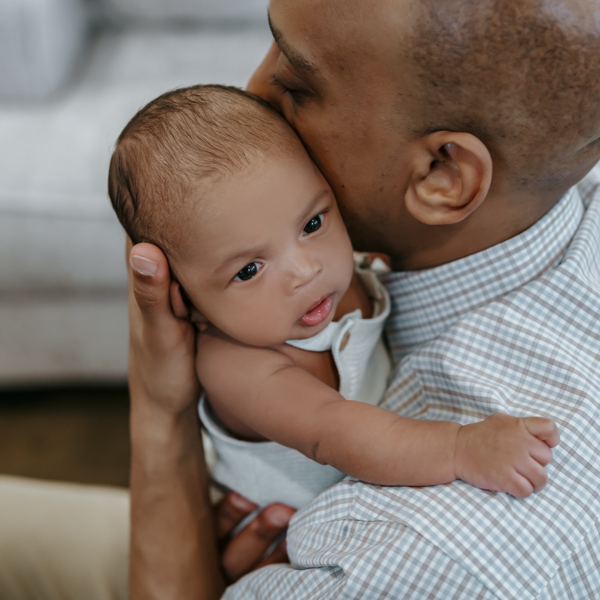 Close-up of father pressing his face against newborn Yohannes, who looks at the camera with wide eyes