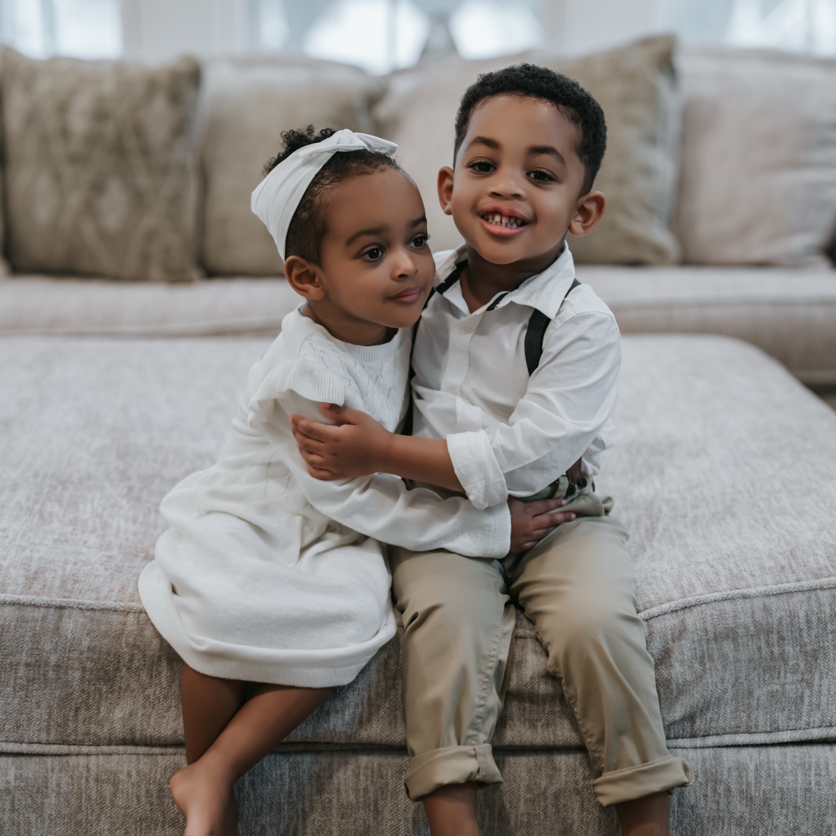 Yohanna and Yonas sitting side by side on the couch, hugging each other and smiling
