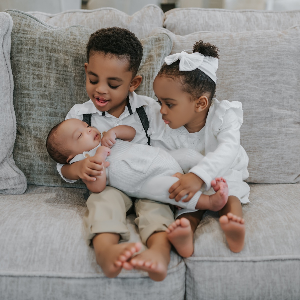 Yonas and Yohanna sitting together on the couch, gently holding sleeping baby Yohannes on their laps
