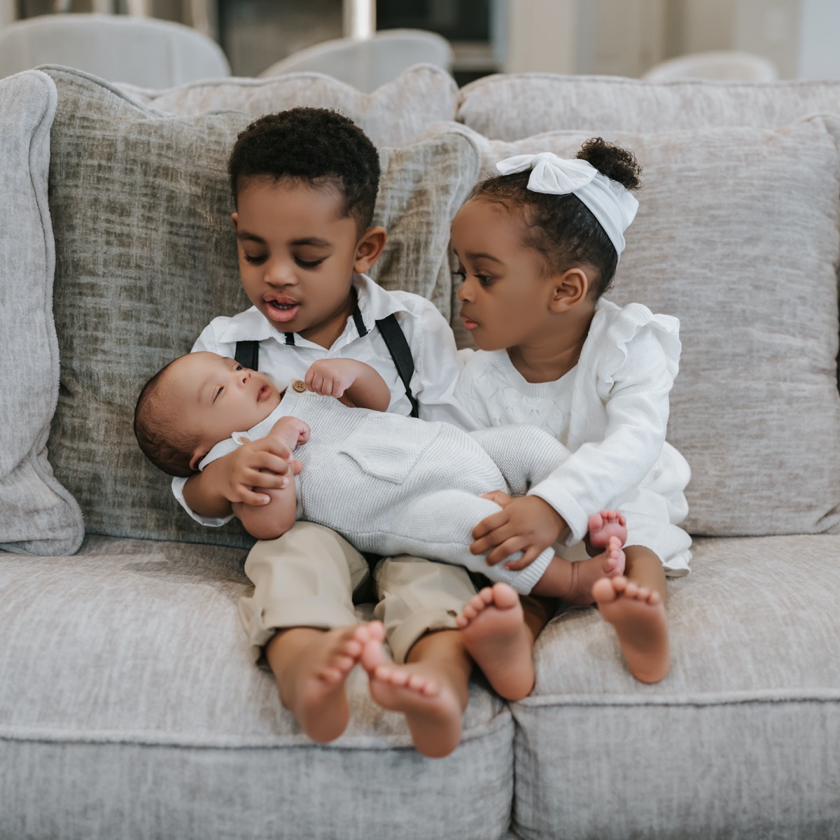 Yonas and Yohanna sitting side by side, carefully cradling newborn Yohannes who sleeps peacefully