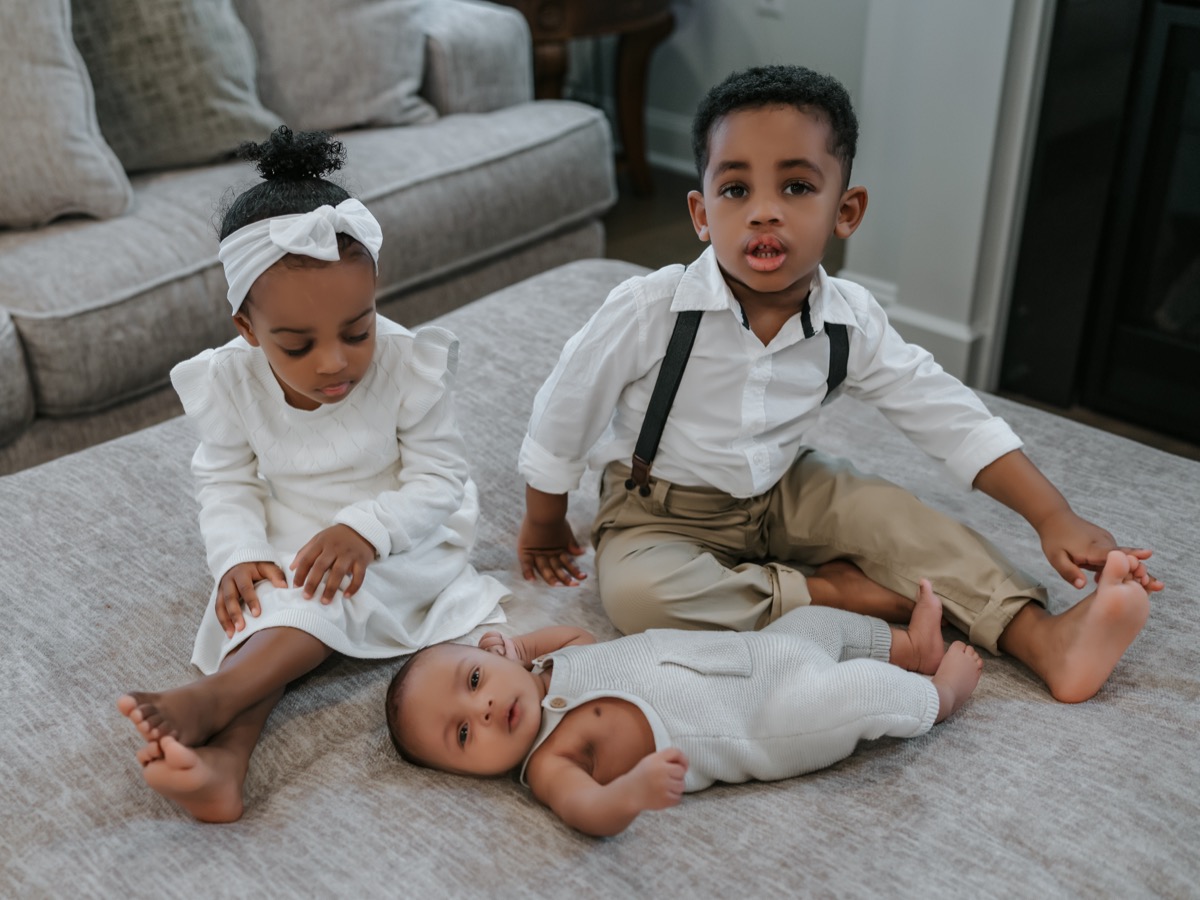 All three siblings together — Yohanna and Yonas sitting with baby Yohannes lying between them on the ottoman