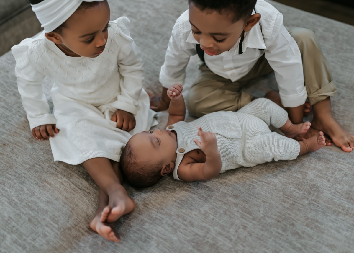 Yohanna and Yonas looking down at baby Yohannes who lies between them with his hand raised