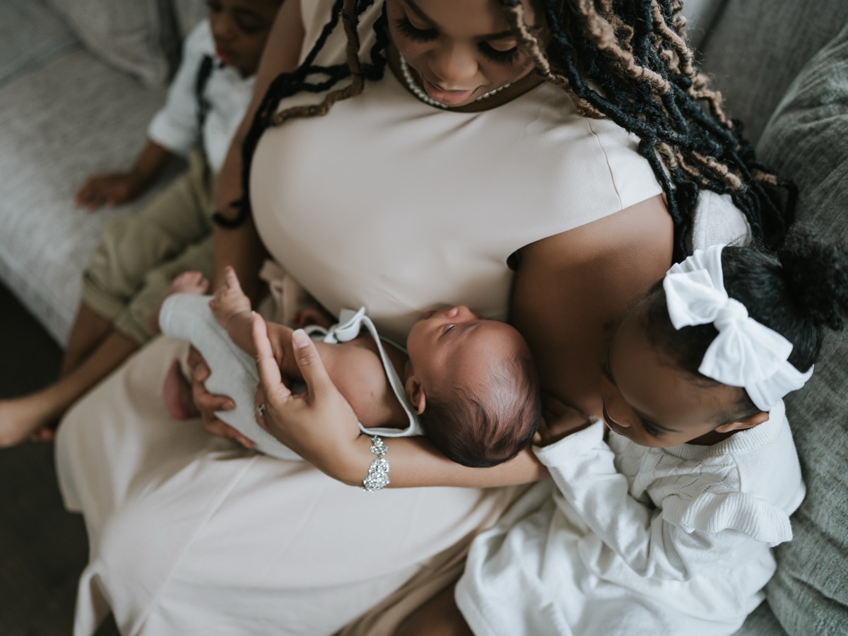 Mother holding sleeping newborn Yohannes while daughter Yohanna snuggles close and a child sits nearby
