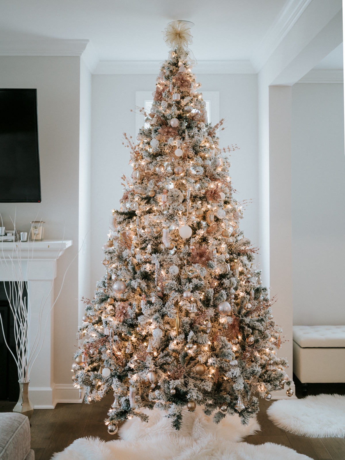Elegant flocked Christmas tree decorated with gold, white, and rose ornaments glowing with warm lights