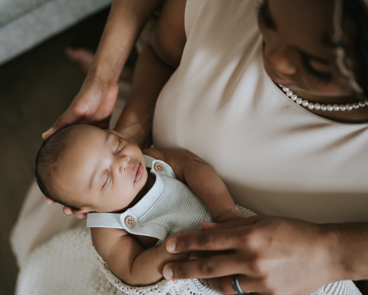 Overhead view of parents gently cradling sleeping newborn Yohannes, mother stroking his head