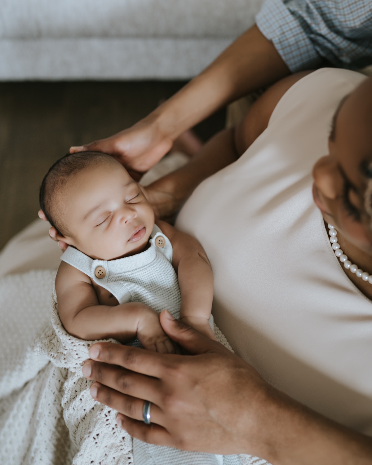 Both parents holding sleeping newborn Yohannes, father's hand gently supporting his head