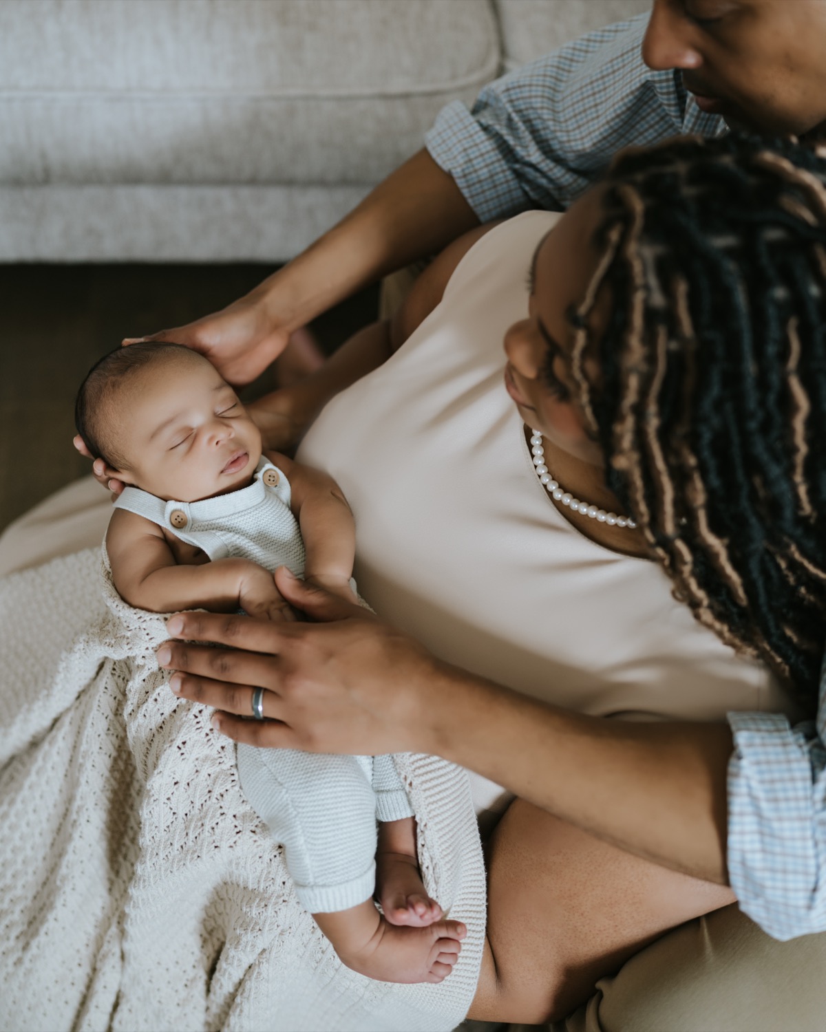 Mother cradling sleeping Yohannes in a knit blanket while father wraps his arm around them both