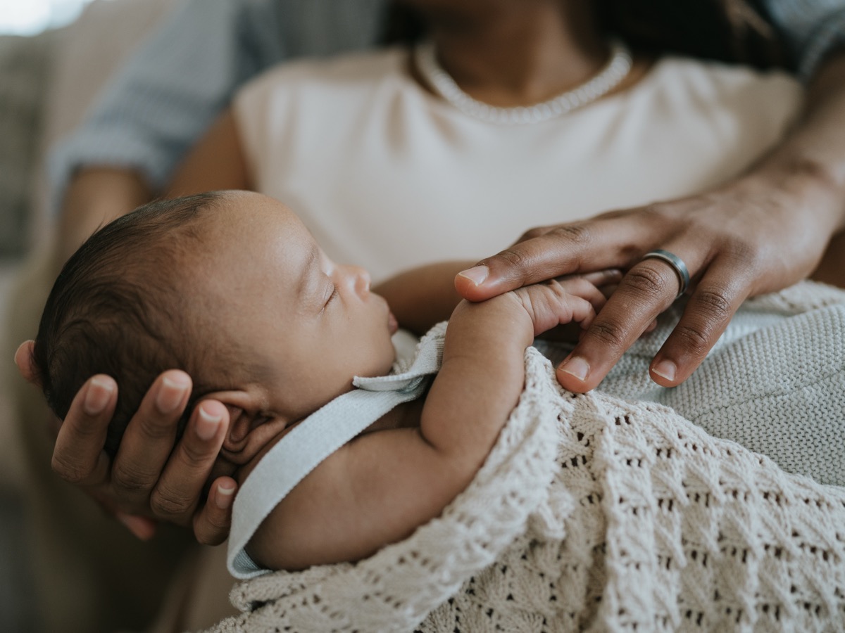 Close-up of sleeping newborn Yohannes with mother's hand on his head and father's hand holding his tiny fingers
